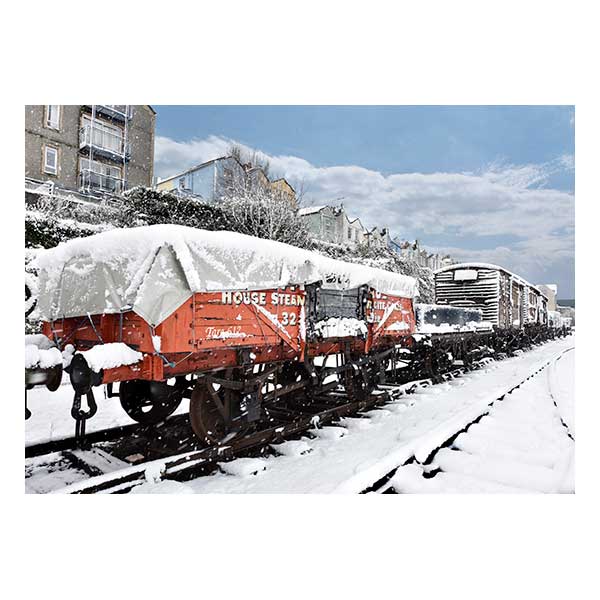 Red train carriage in snow with houses in background